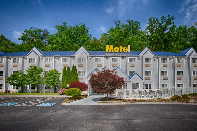Best Hotel in Pigeon Forge TN showing a large budget-friendly motel exterior surrounded by trees and parking area, ideal for comfortable stay near Smoky Mountains attractions.