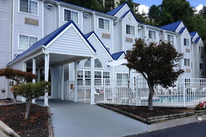 Places to stay in Pigeon Forge TN showing exterior view of a budget-friendly hotel with pool, parking area, and easy access to Smoky Mountains attractions for families and travelers.